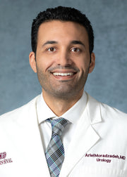 A man in a white suit and tie, smiling, highlighting formal attire.